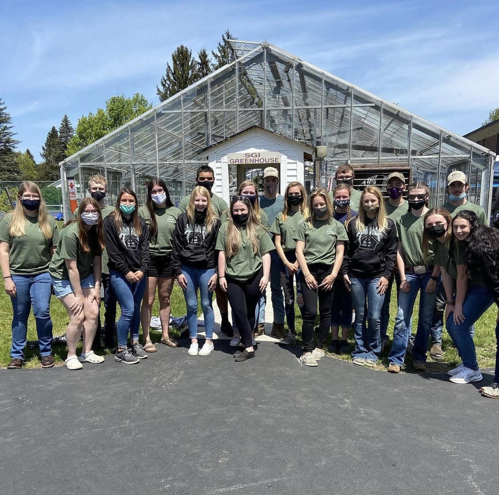 Students stand in front of SGI High School's greenhouse