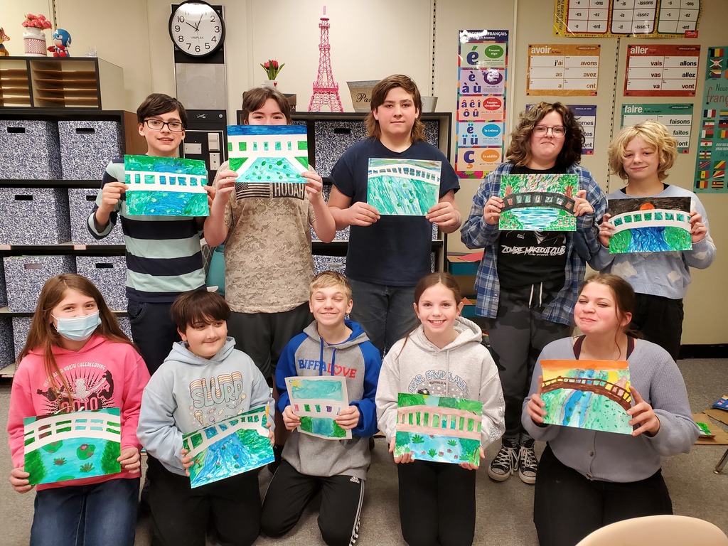 10 students hold up paintings.