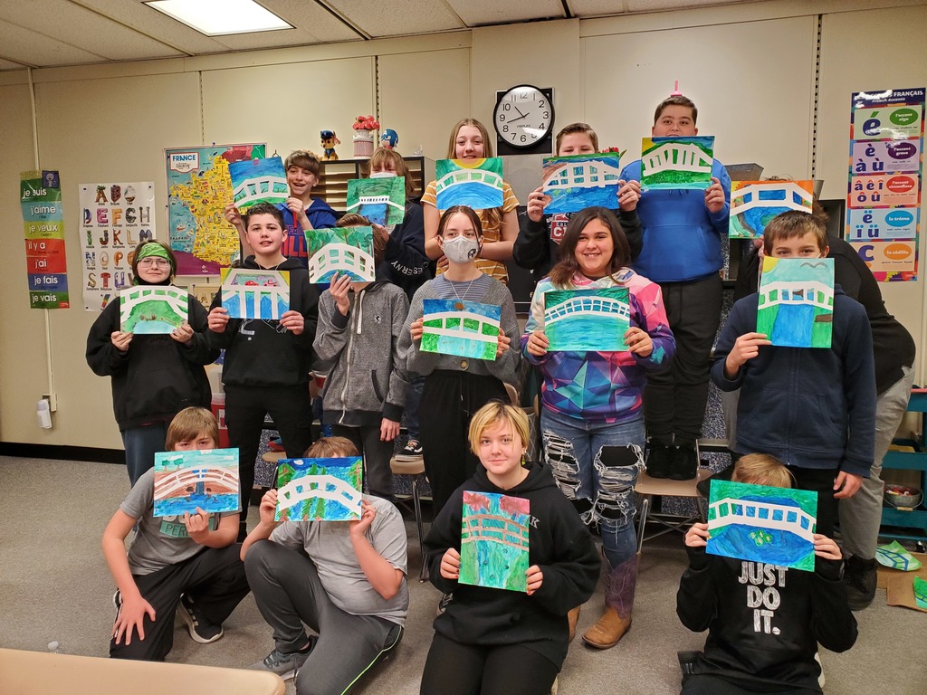 15 students hold up paintings. 