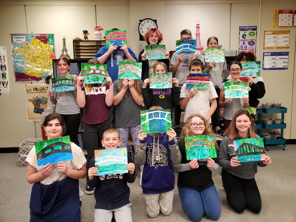 15 students hold up paintings.