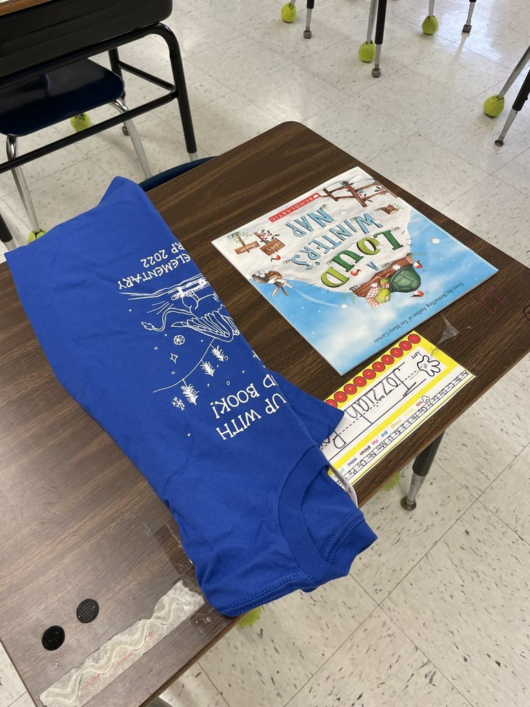 A shirt and book sit on a table with flooring below. 
