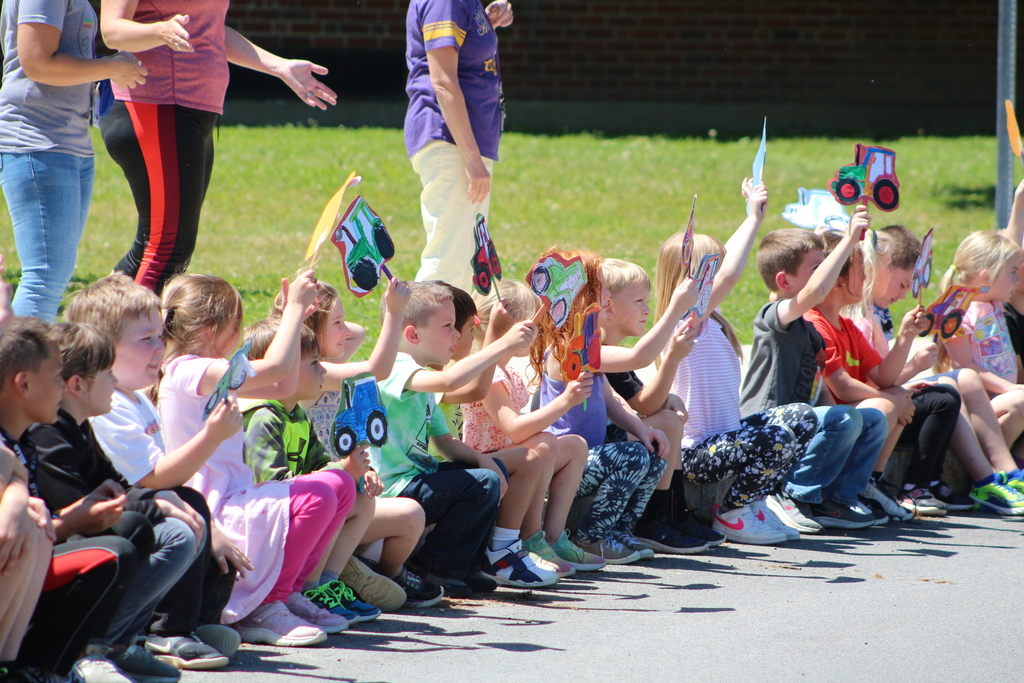 Students wave paper tractors in the air to welcome the SGI HS students during the Tractor Parade.